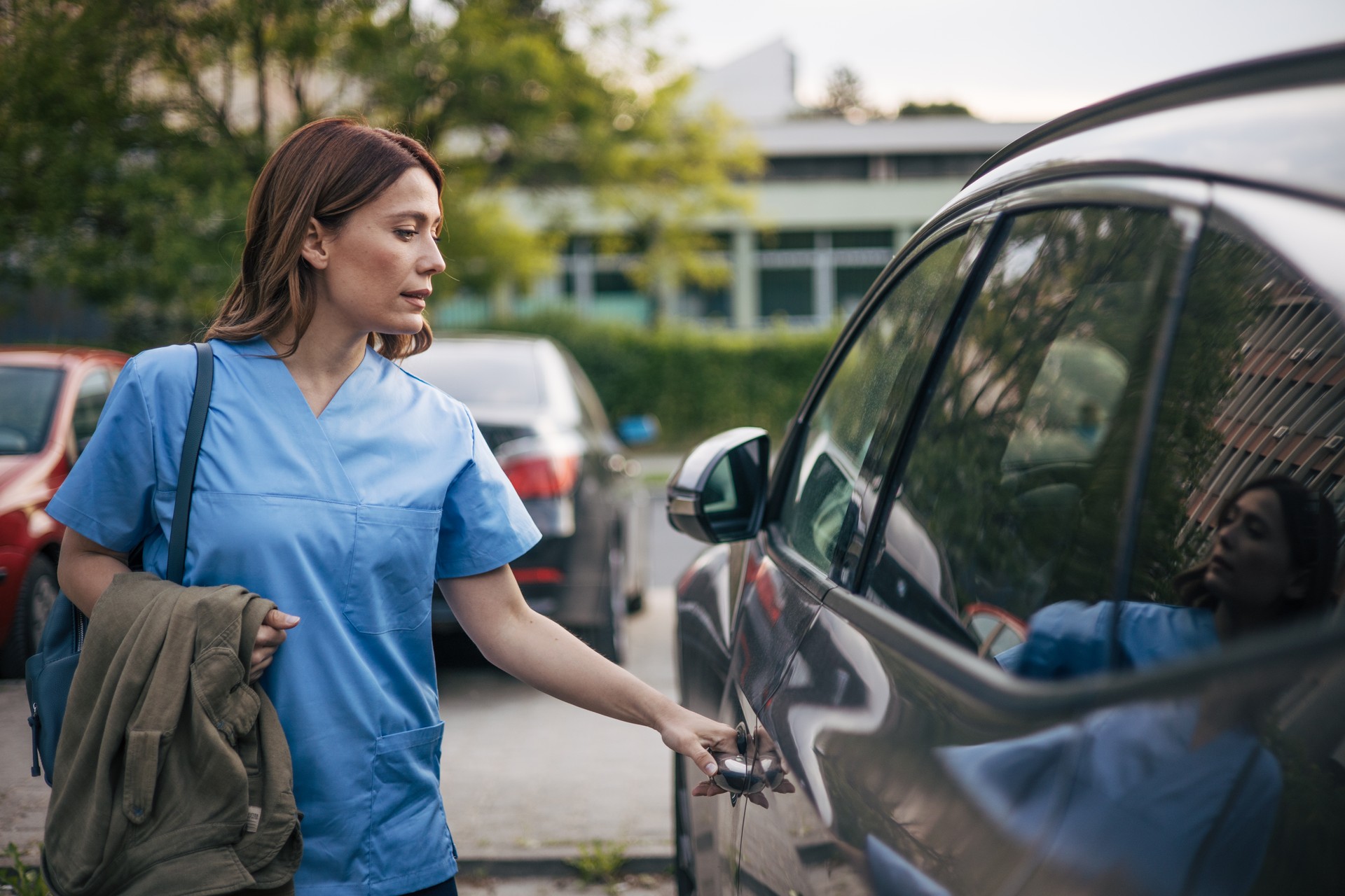 a beautiful female doctor has finished her work and is getting into the car.