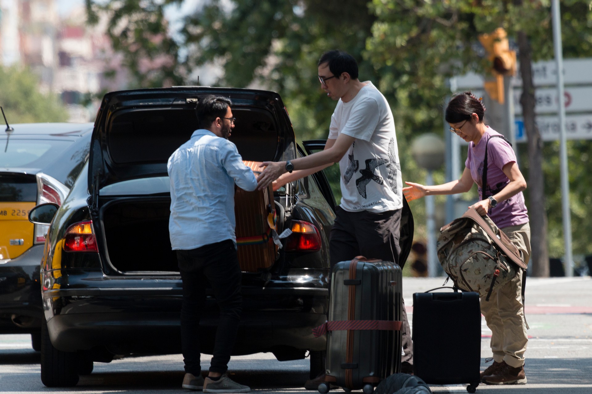 Barcelona, Spain, July 2018:  Transport and traffic. Taxist help tourists to unloading baggage.